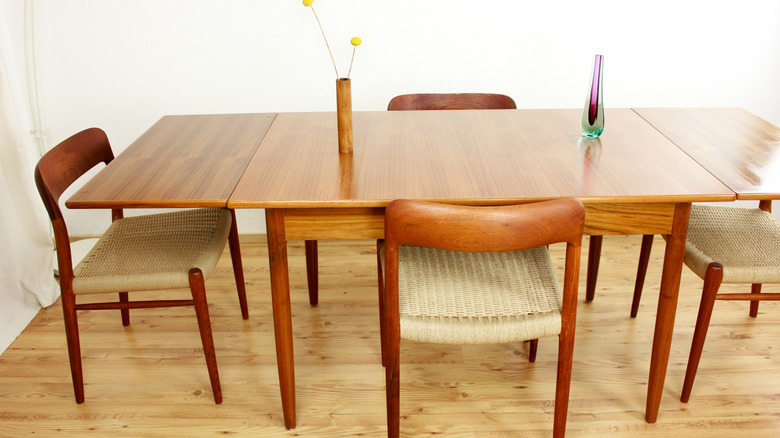 A mid-century modern dining table in a walnut finish with four wooden chairs