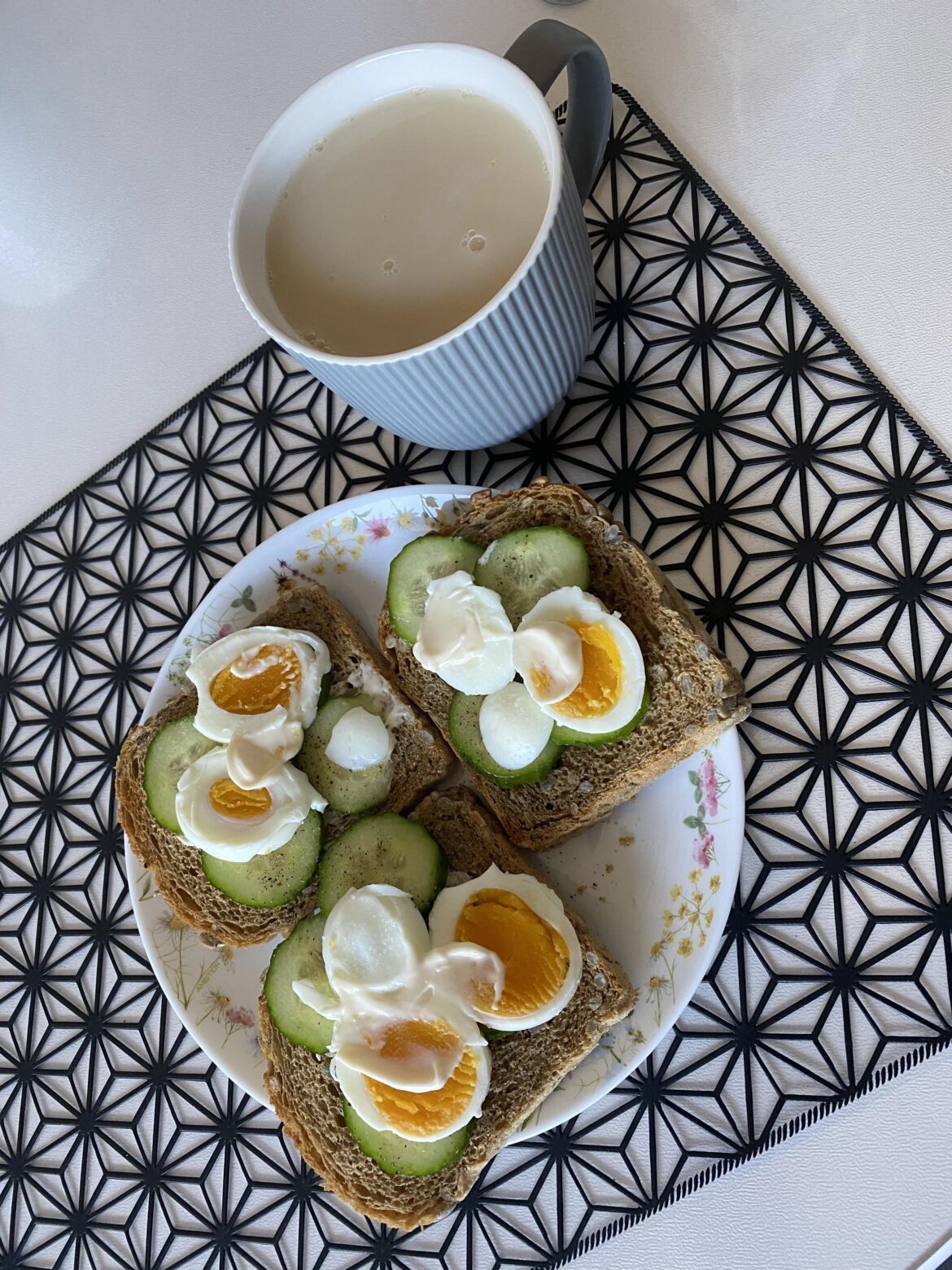 Toasts with some butter, a cucumber, an egg with a bit of mayonnaise and a cup of milk tea