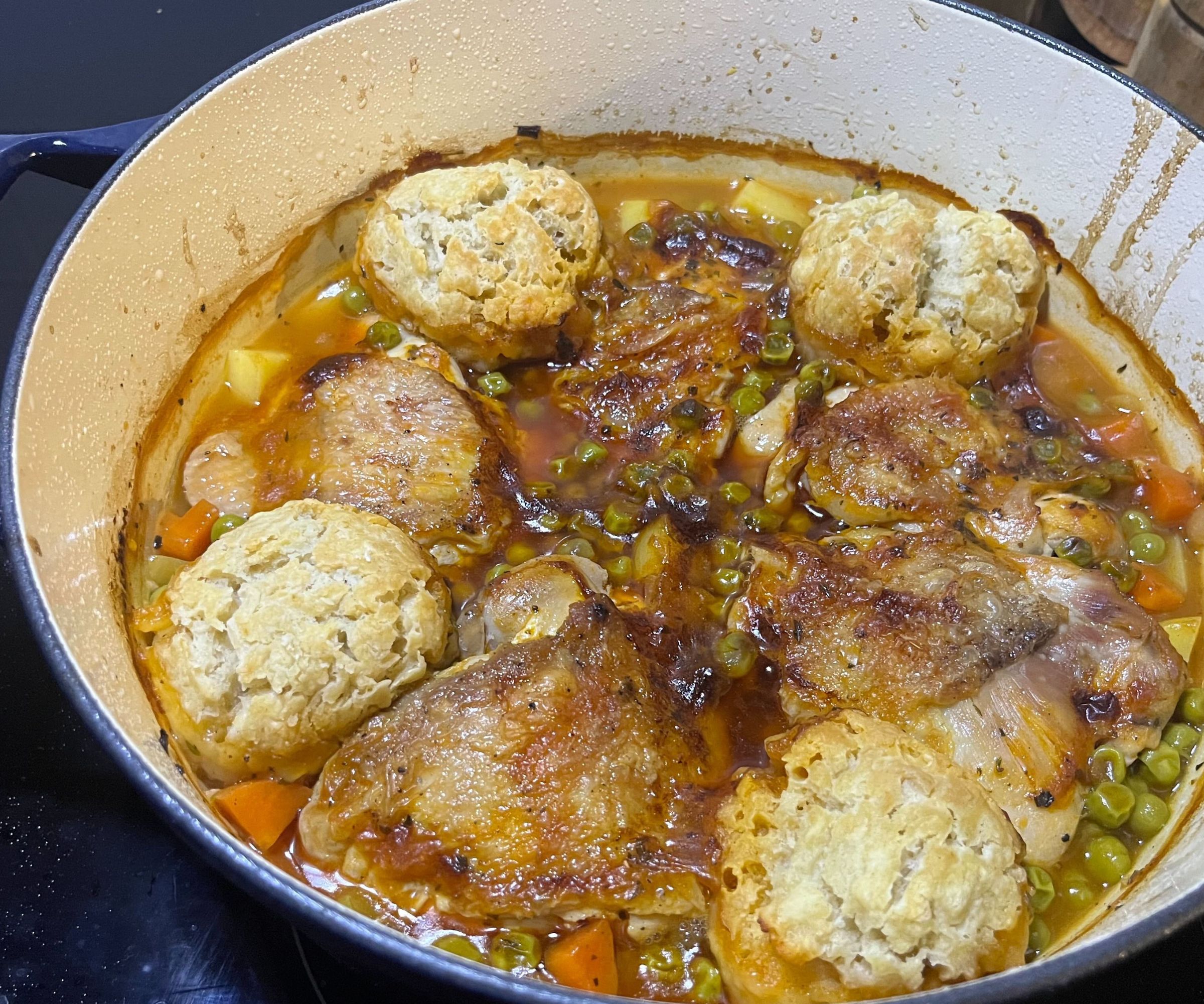 A golden chicken stew in a Dutch oven on a black electric stove