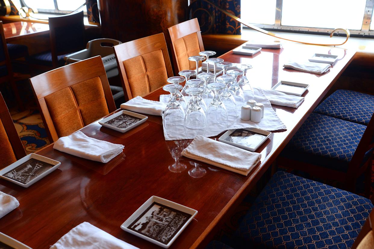 Glasses, napkins, and square plates on a rectangular table in the Carnival Glory Dining Room