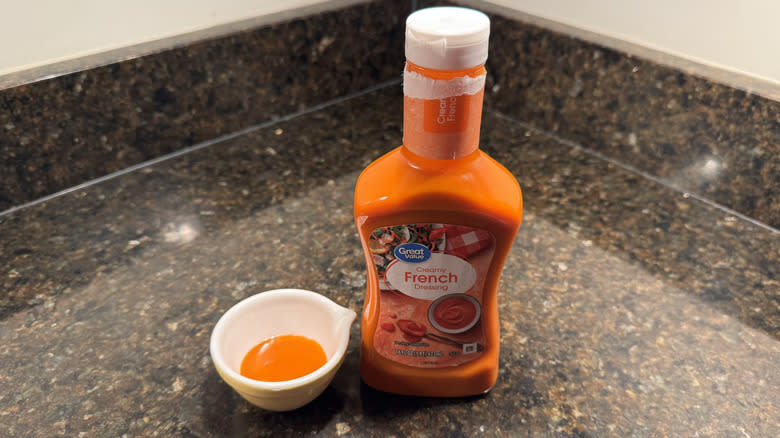 Great Value French dressing on a countertop next to small white dish containing dressing