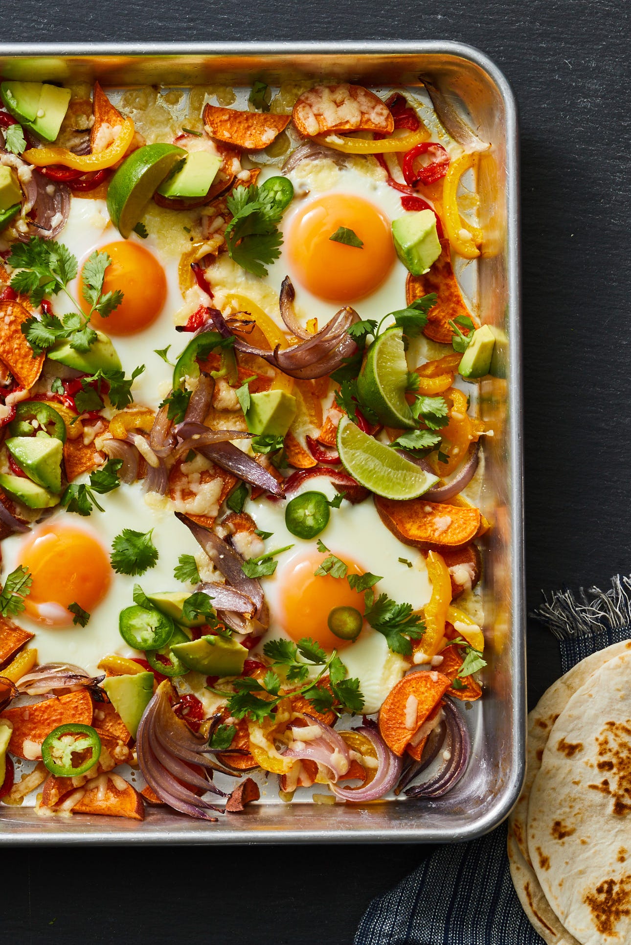 sheet pan breakfast fajitas topped with sunny side up eggs