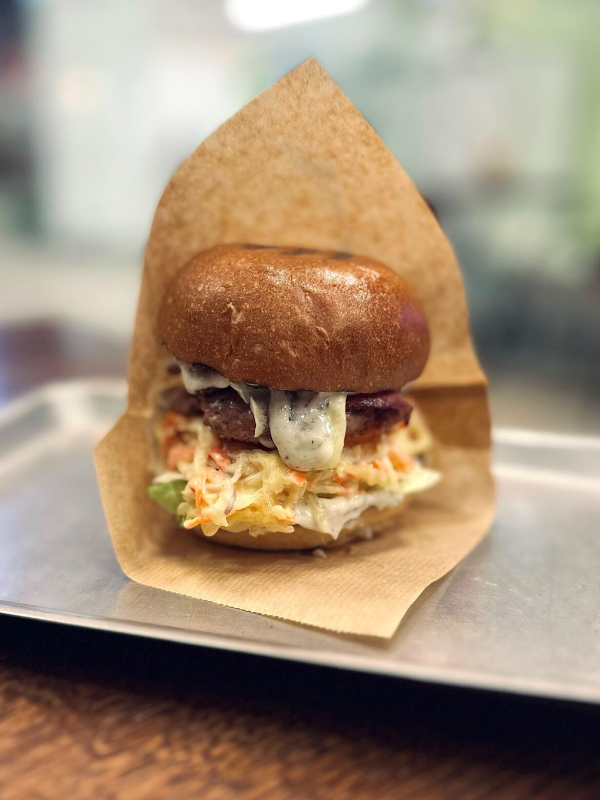 Burger with brioche bun, beef patty, lettuce, bacon, coleslaw salad, truffle mayo and cheddar cheese