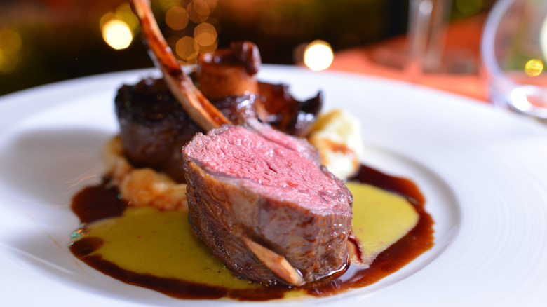 Gourmet tomahawk steak on white plate on top of sauce