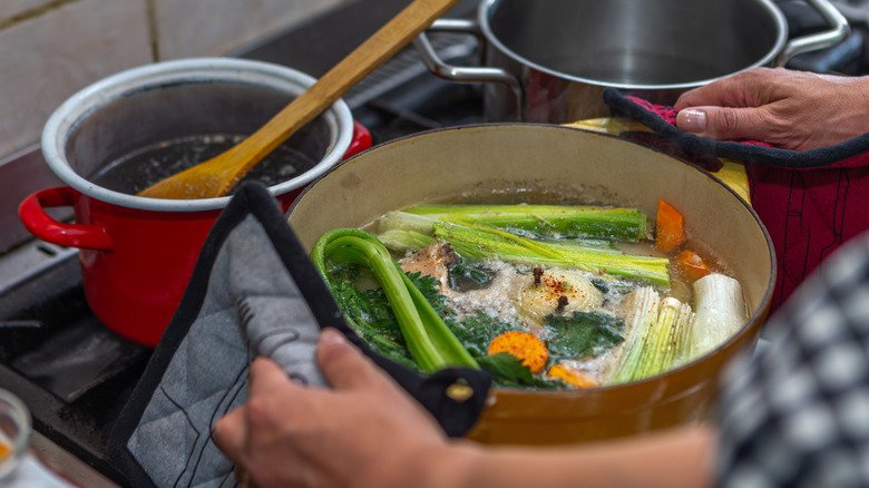 Person holds pot of vegetable stock on stovetop