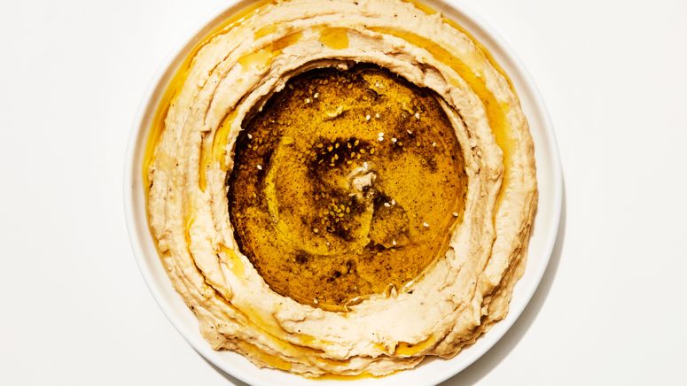 Overhead shot of hummus swooshed around the edge of a bowl with a garnish of olive oil and za'atar in the center.