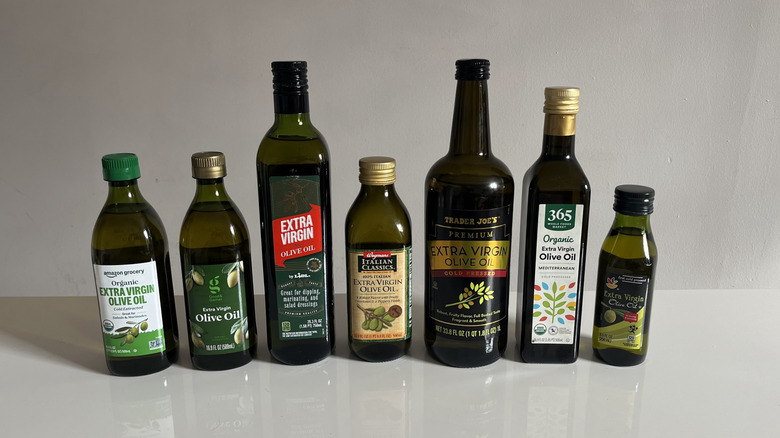 A lineup of store-brand olive oils on a white table
