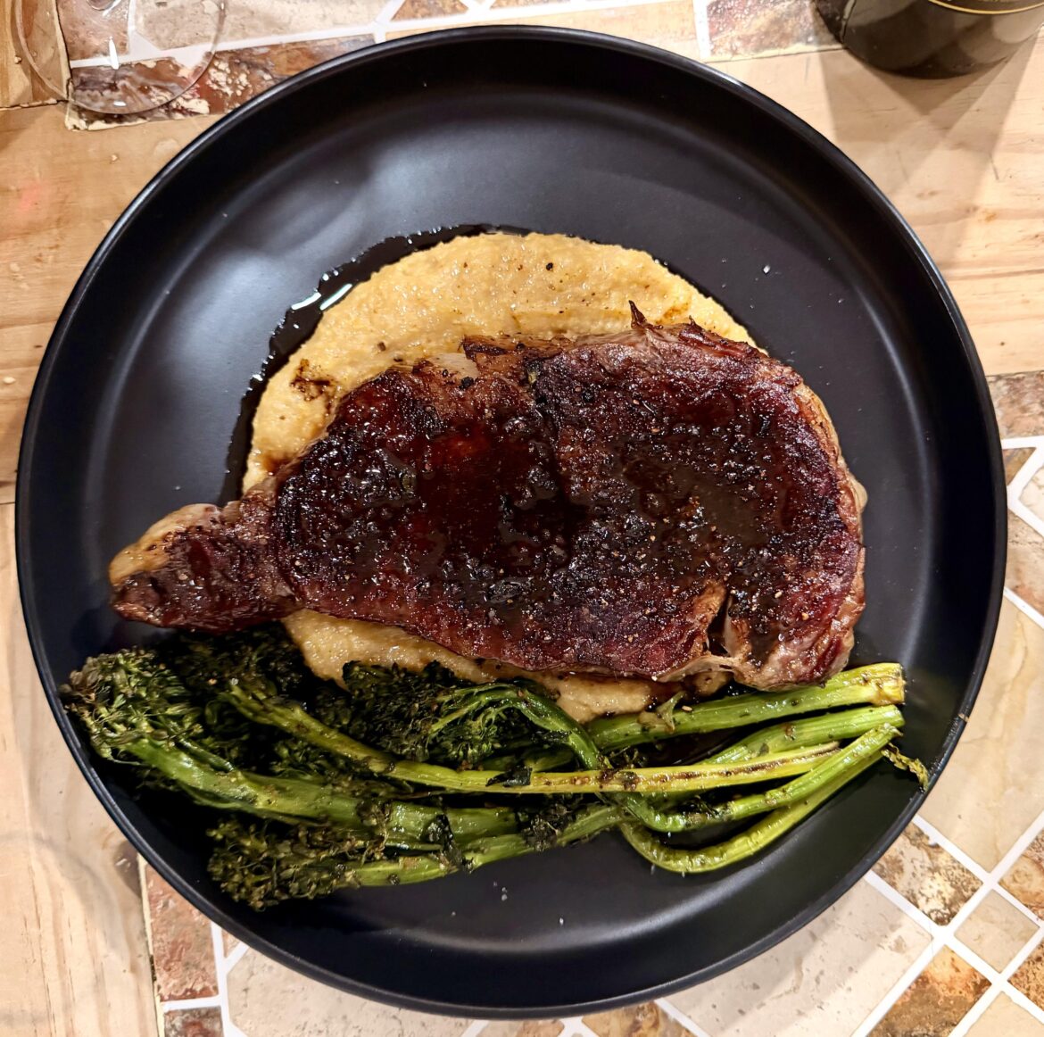 Reverse seared Delmonico steak topped with pan sauce with creamy polenta and roasted broccolini