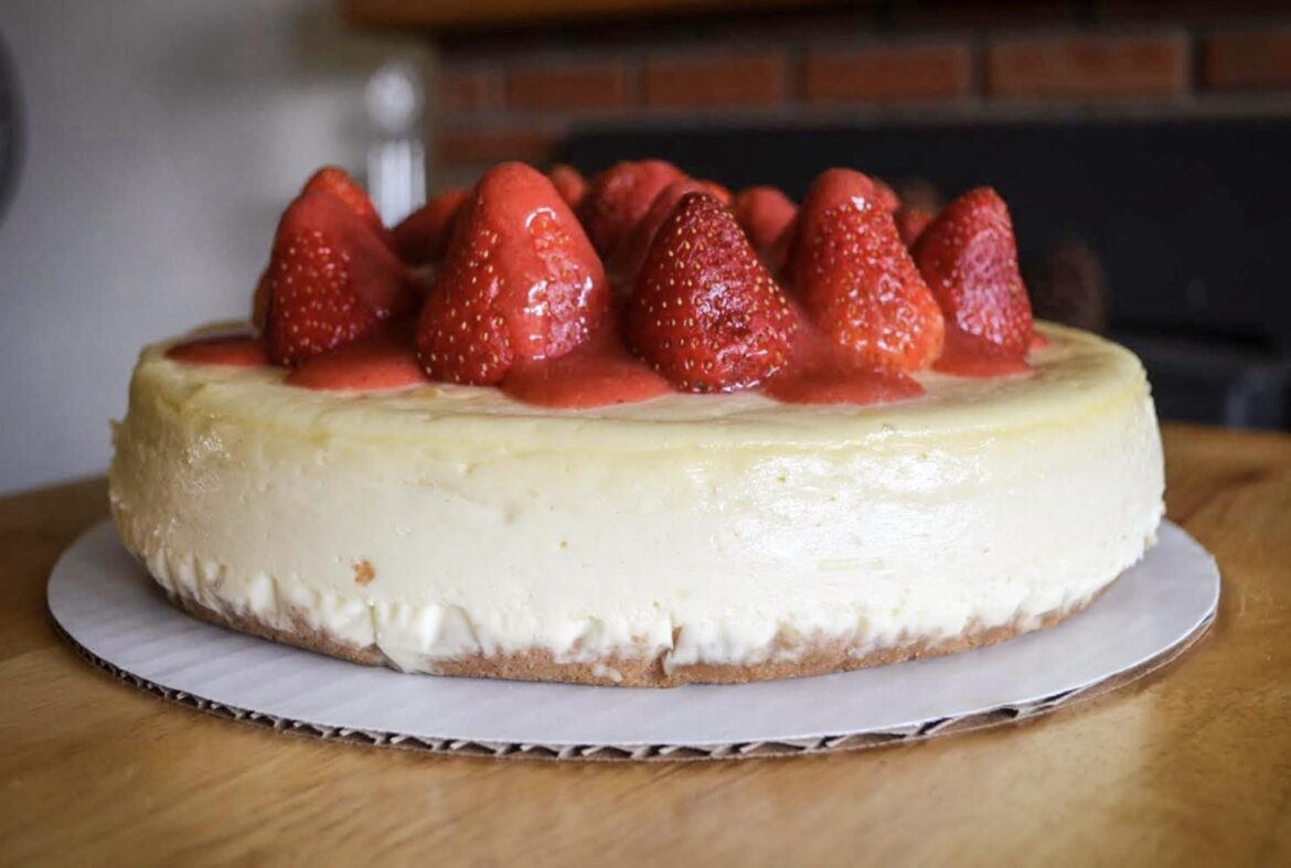 A cheesecake with lots of edible strawberries.