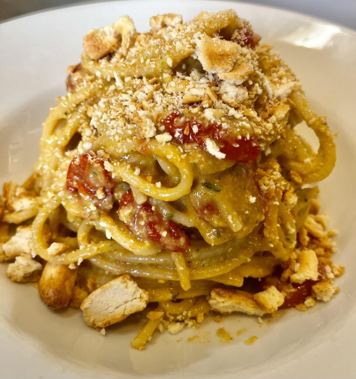 Spaghetti with zucchini pesto, baked tomatoes, and crumbled Apulian taralli.