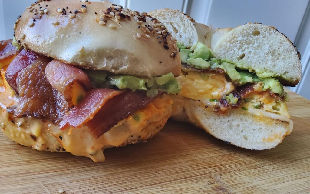 Bacon egg cheese avocado breakfast sandwich on everything bagel.