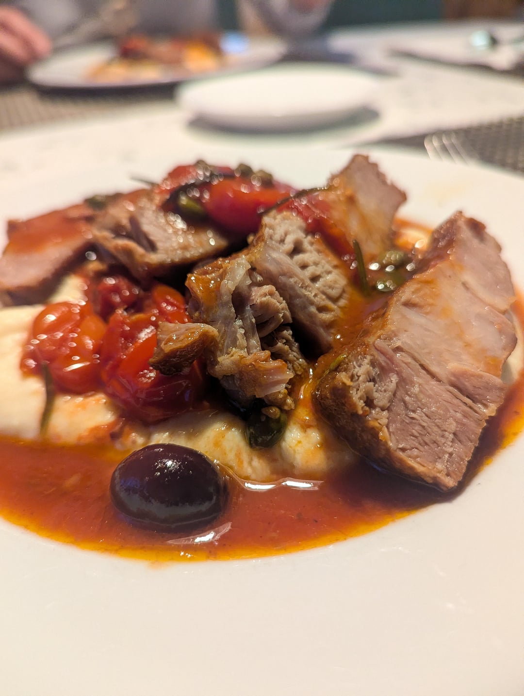 Pork neck on semolina porridge with a sauce of olives, capers and ...