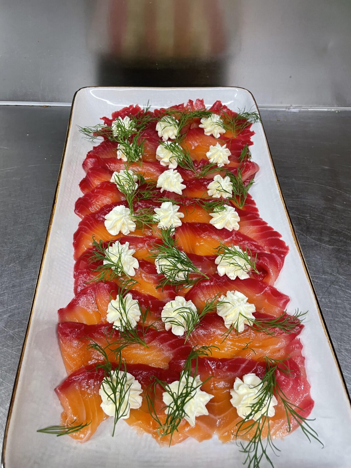 Cured salmon dyed with beetroot topped with feta cream