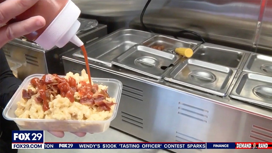 Person pouring sauce onto a dish.