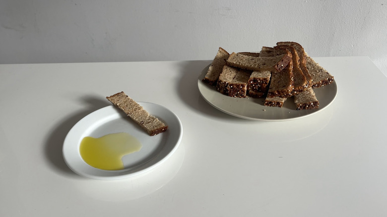 Plate of sliced bread pieces sitting next to a dish with olive oil