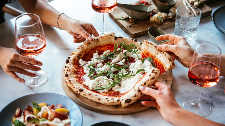 People grabbing pieces of pizza at an Italian restaurant