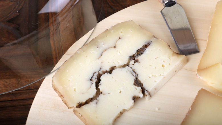 A wedge of Moliterno al Tartufo served on a wooden plate