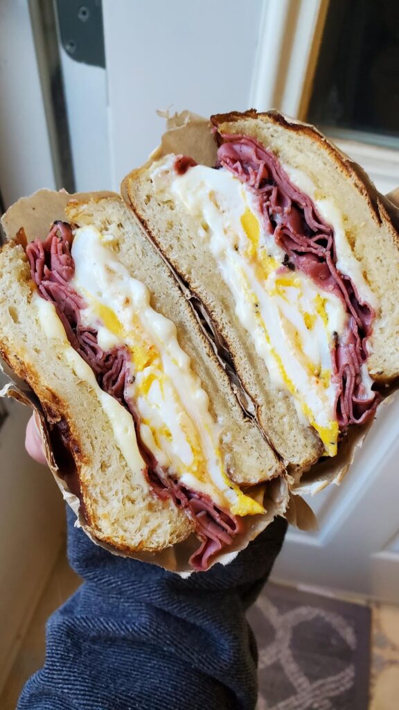 Two fried eggs, horseradish sauce, pastrami, and Cooper cheese on pretzel roll.