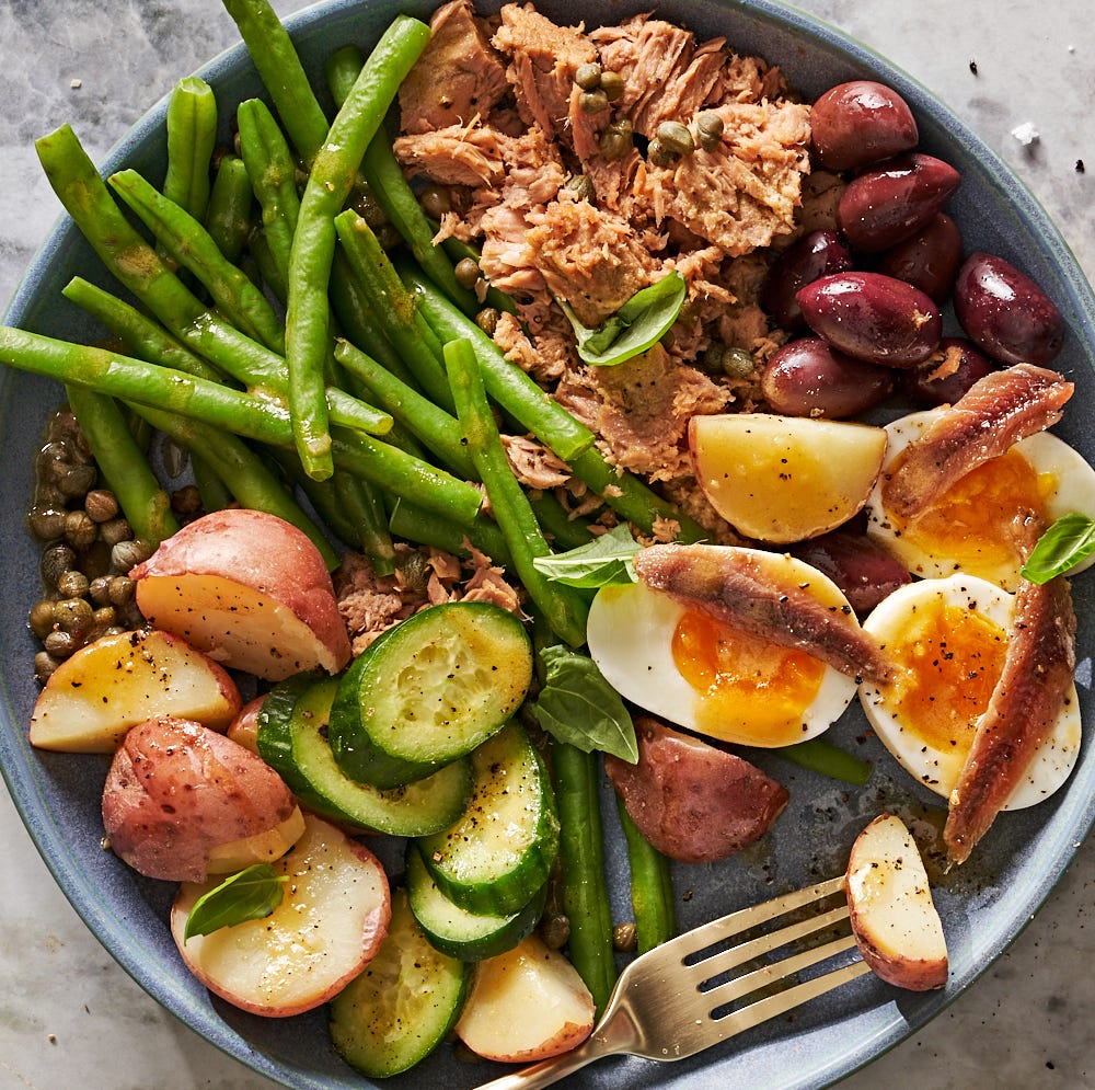nicoise salad with tuna, jammy eggs, anchovies, green beans, potatoes, cucumbers, olives and capers