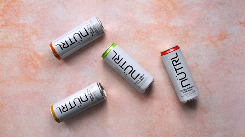 Cans of Nütrl laying on pink background