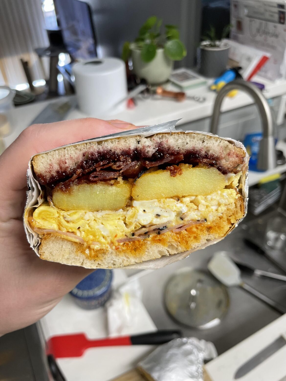 Breakfast Sangweecho. Two eggs, crispy bacon, marionberry jam, roast potatoes, griddled honey ham, American cheese, and Calabrian chili mayo on bacon fat griddled sourdough.