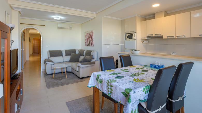 An open-concept room where the living and dining areas are defined by rugs