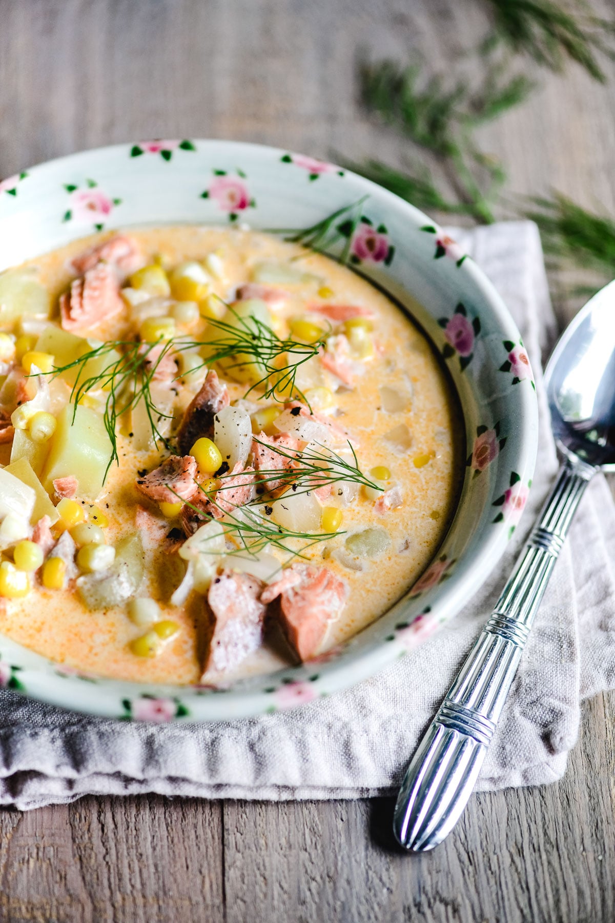 Salmon and Corn Chowder in a green bowl with spoon and fresh dill