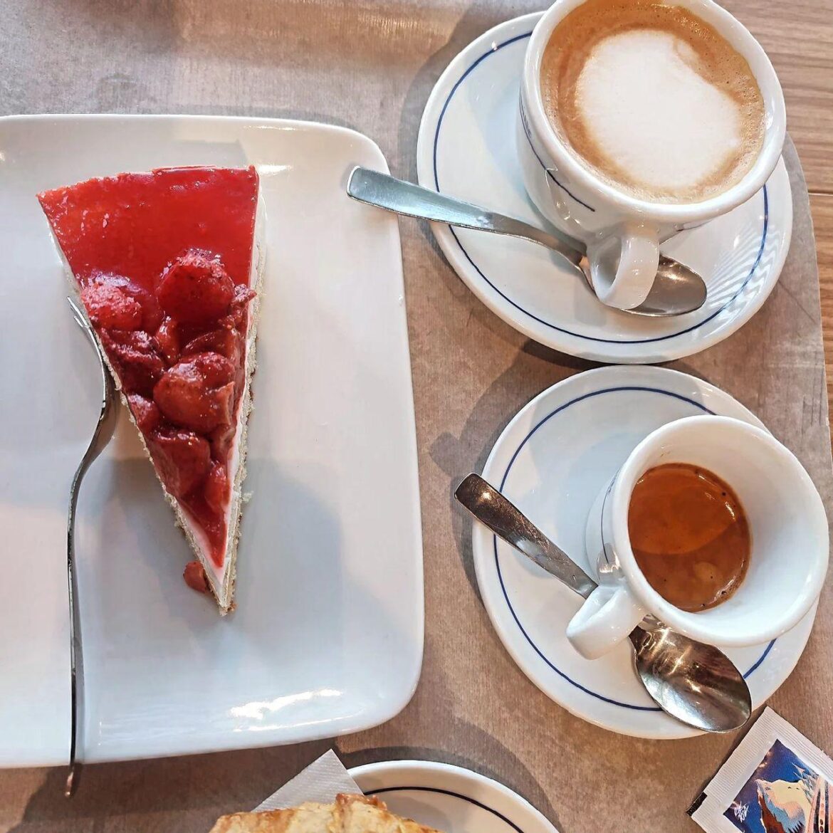 Cappuccino and espresso accompanied by a slice of strawberry cake