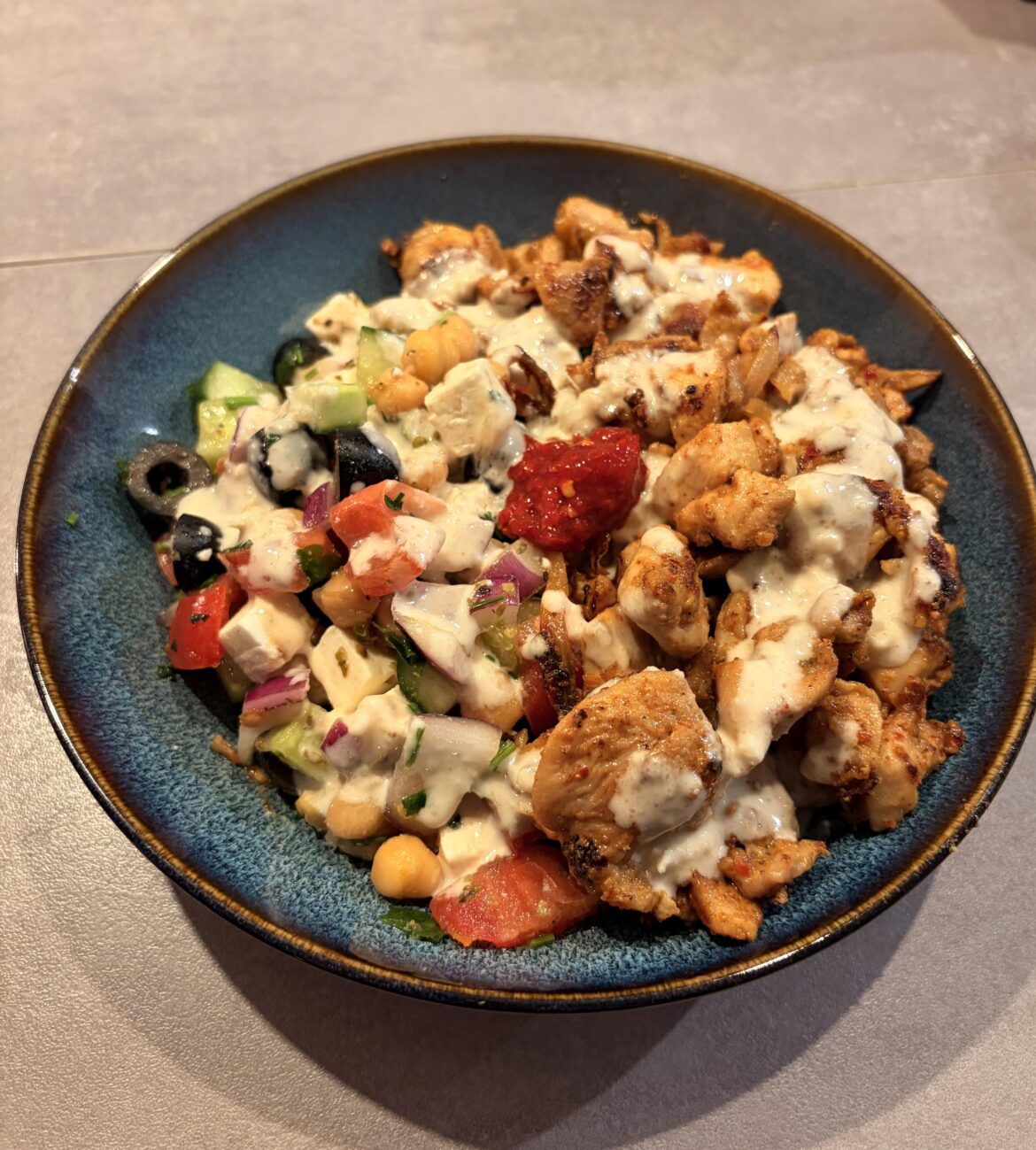 Greek salad with chickpeas, Middle Eastern spiced chicken, tahini sauce and spicy pepper paste