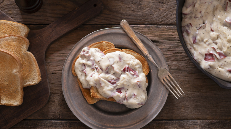 Plate with chipped beef on toast, with extra toast, and a pan of gravy