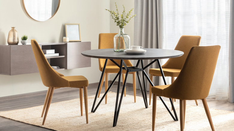 Dining room with a round black table and four orange chairs and a floating buffet