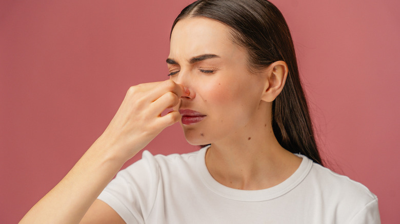 A young woman pinches her nose