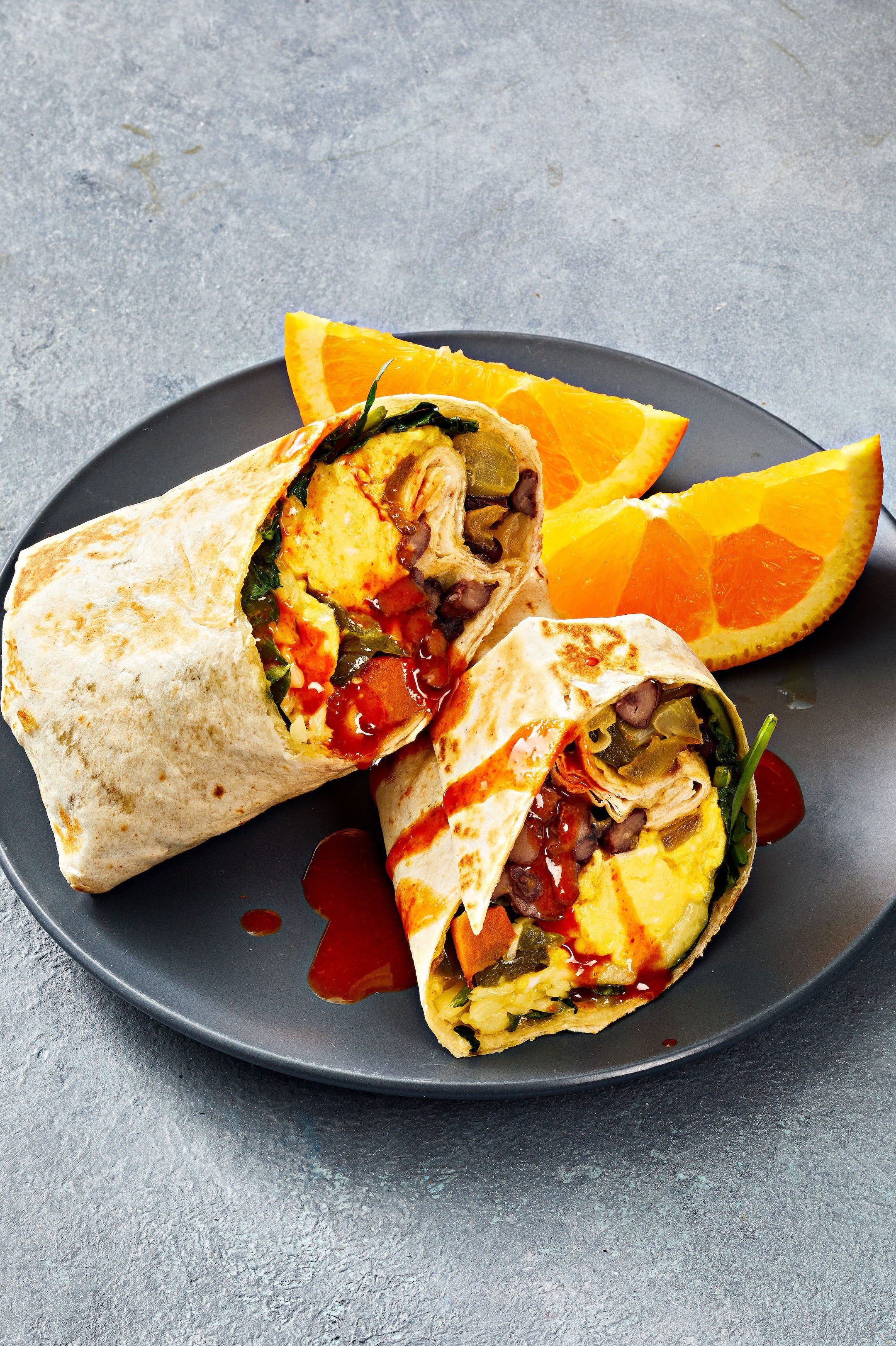 sweet potato breakfast burritos with hot sauce drizzled on top