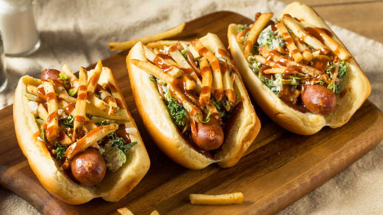Three Polish boy hot dogs on wooden cutting board