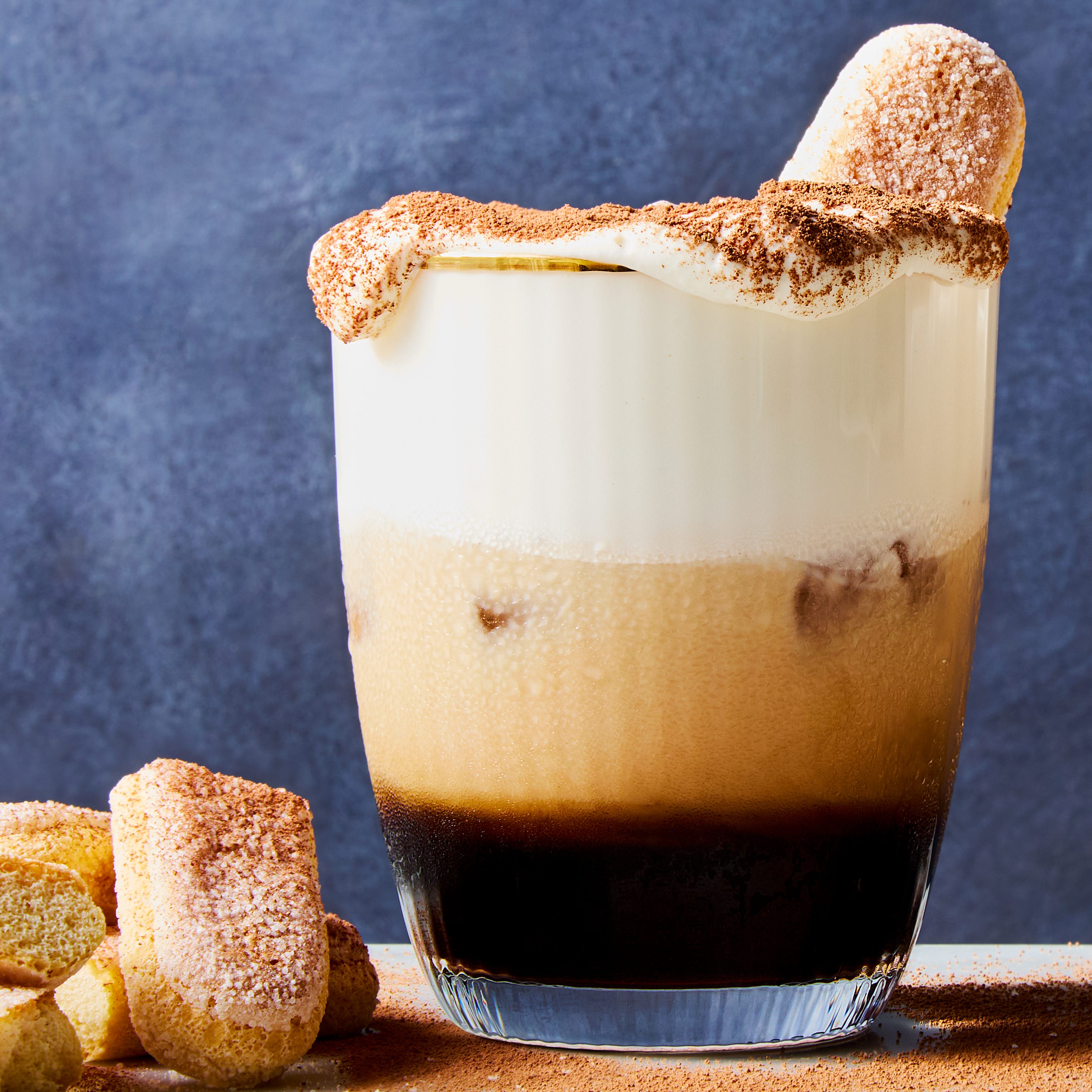 white russian cocktail topped with whipped cream, cocoa powder, and a lady finger