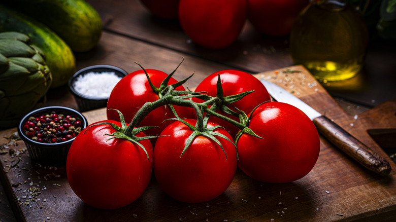 Ripe bunch of tomatoes on vine on a wooden cutting board