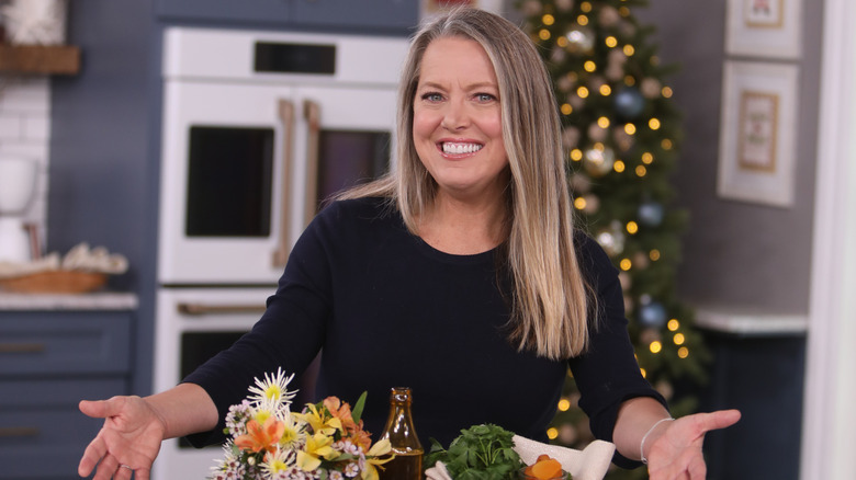 Melissa d'Arabian posing with tray of food and flowers inside kitchen