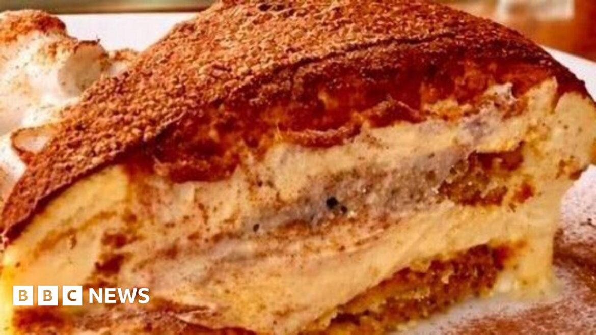 Giovanni Scidetta, known to regulars as John, dressed in chef's whites and holding a plate of tiramisu