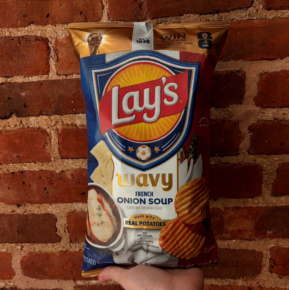 Bag of Lay’s Wavy French Onion Soup chips held against a brick wall.