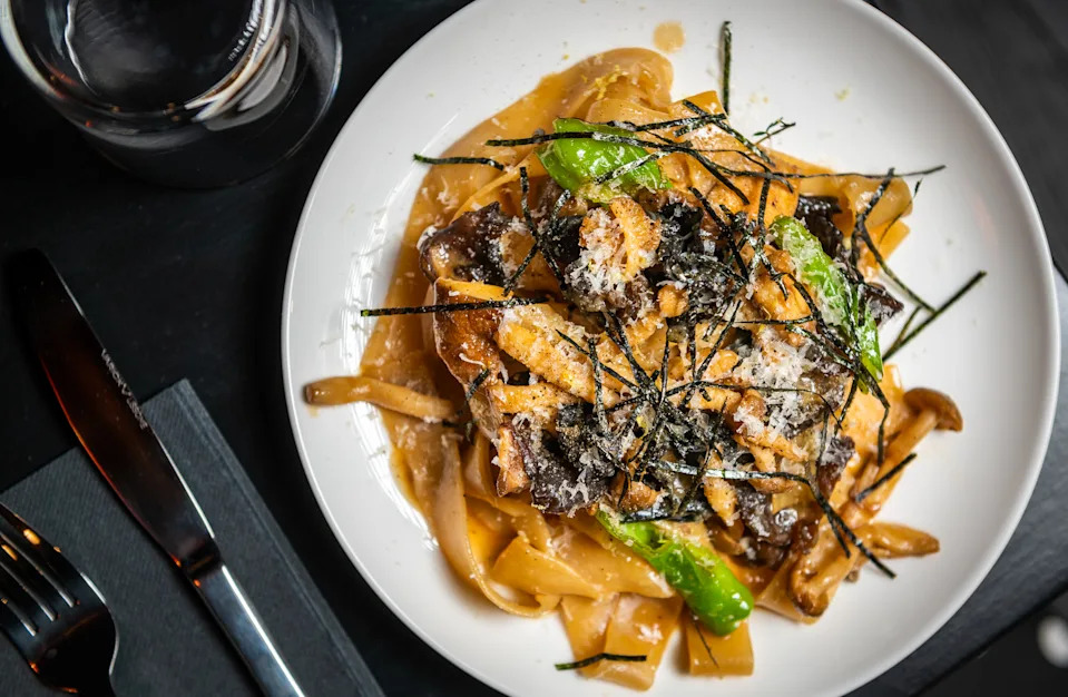 A plate of Japanese mushroom and shishito pepper pappardelle at Tonari gets garnished with pecorino cheese and nori.