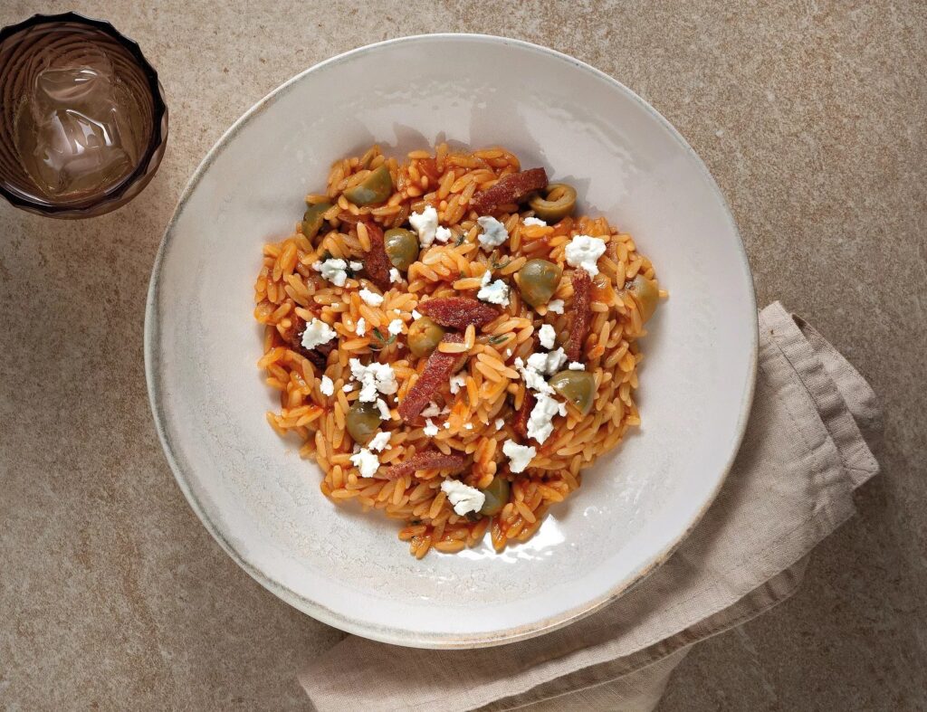 Giouvetsi with tomato, salami, olives and feta cheese