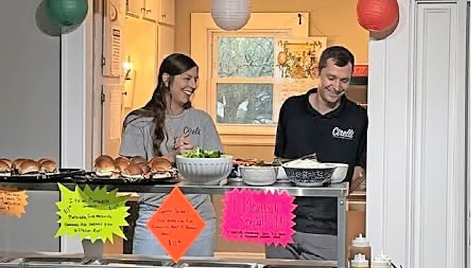 Staff members at a food service station smiling and interacting.