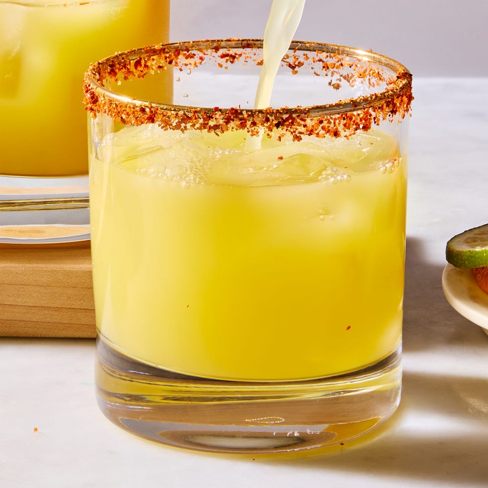 A cocktail with a spicy rim and ice, garnished with citrus.