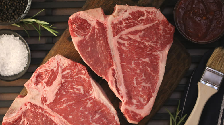 Two raw porterhouse steaks on a cutting board