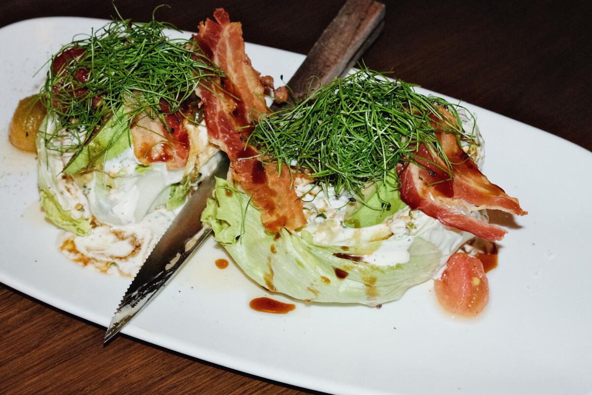 Two iceberg heads of wedge salad featuring avocado, cured cherry tomatoes, bacon and house-made buttermilk dressing