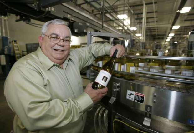 ** ADVANCE FOR TUESDAY MAY 29 ** Fred Franzia holds a bottle of Charles Shaw chardonnay wine off the bottling line at the Bronco Wine Company facility in Napa, Calif., Tuesday, April 17, 2007. An astounding 55,000 cases a day are coming out of this Napa Valley bottling plant, more than some upscale wineries make in a year. And it's owned not by some blue-blooded purveyor of high-end reds but by Fred Franzia, famous for Two Buck Chuck and the ten bucks taboo, as in: No wine is worth more than $10. (AP Photo/Eric Risberg)