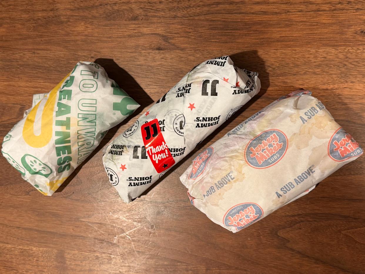 Subway, Jimmy Johns, Jersey Mikes sandwiches in wrappers on table