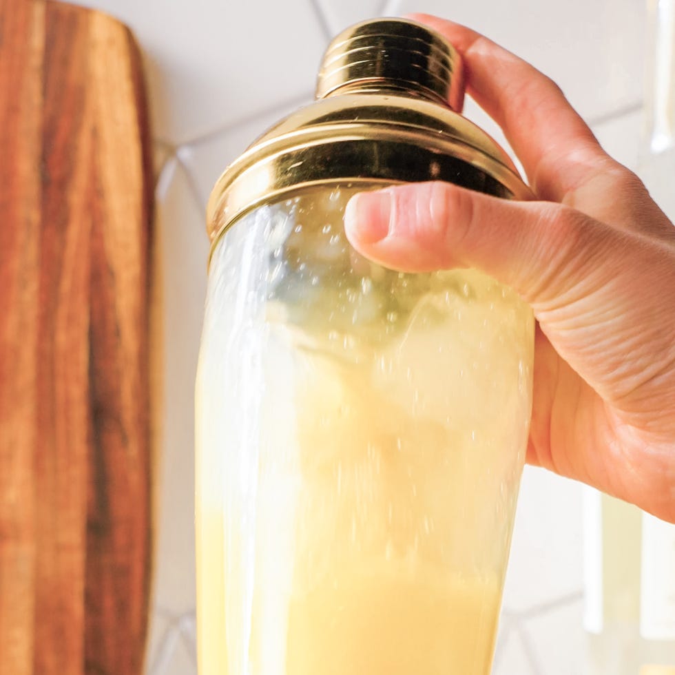 a cocktail shaker being held with a golden lid.