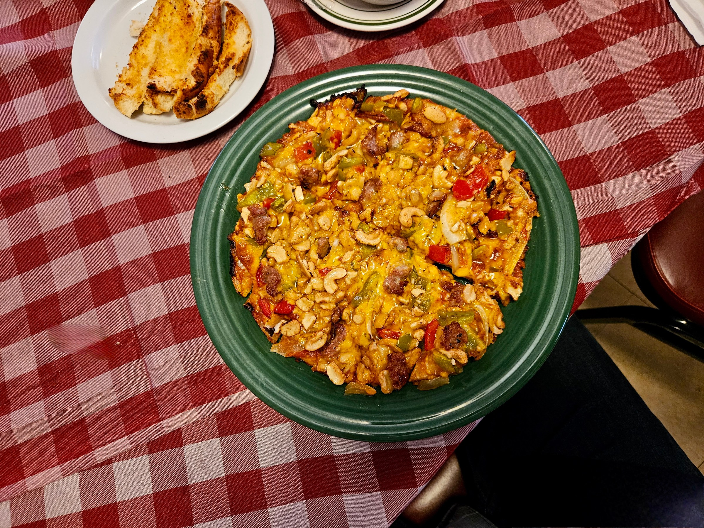 Overhead shot of a thin-crust pizza on a red checkered table at Casale’s Halfway Club.