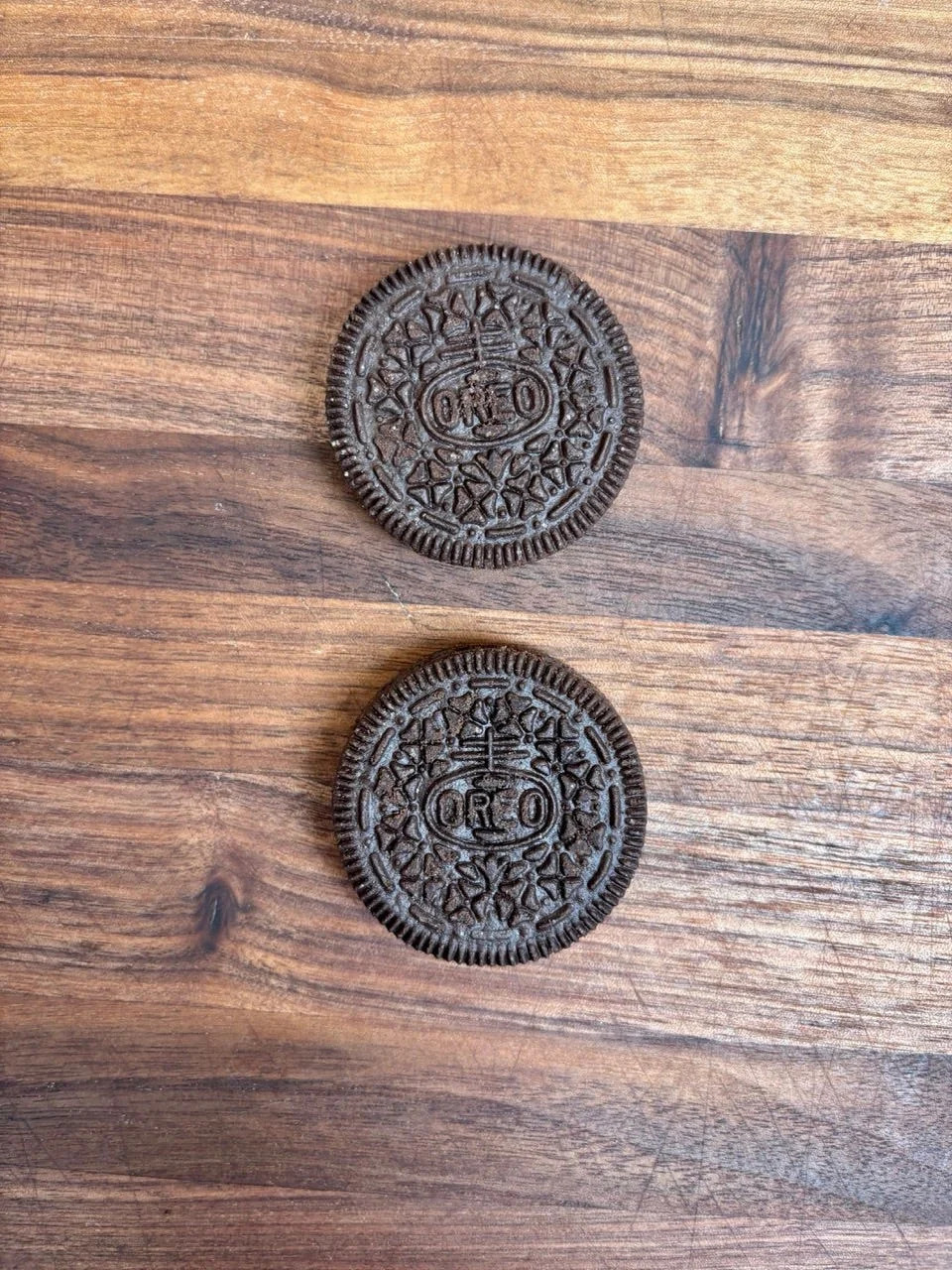 two chocolate sandwich cookies on a wooden surface